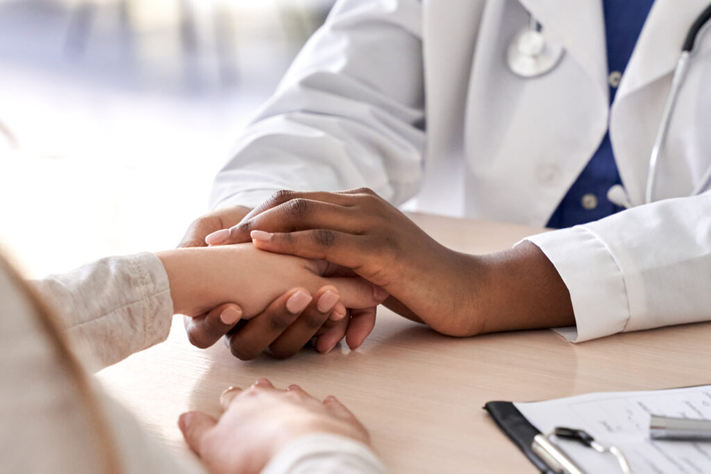 Doctor holding patient's hand in a comforting gesture.