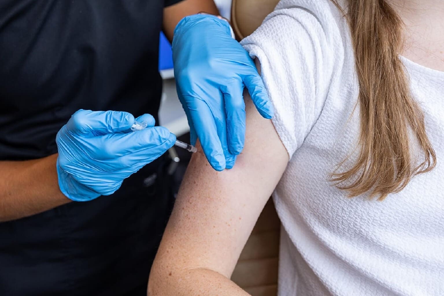 Person receiving vaccination in upper arm.