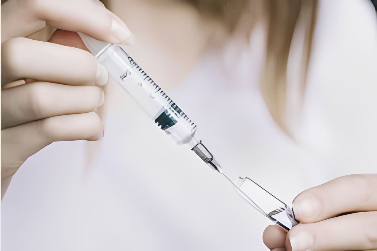 Person preparing syringe with liquid medication.