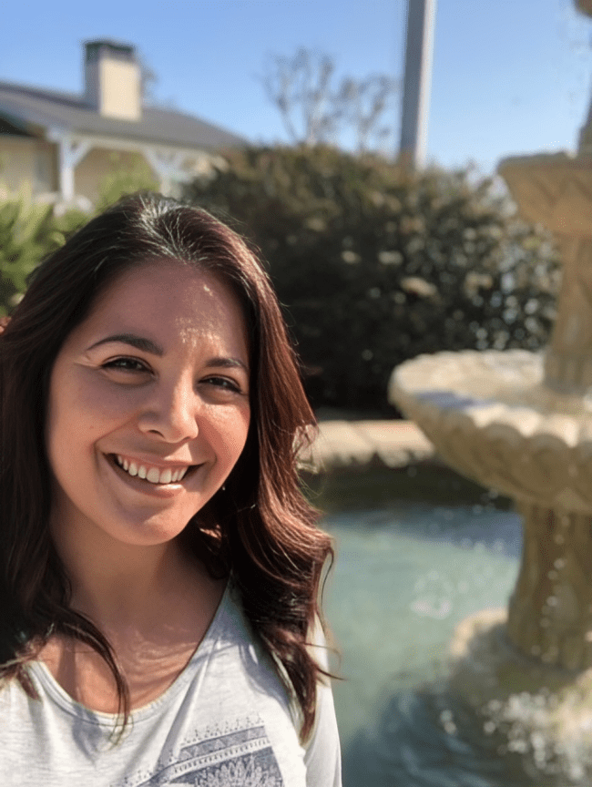 Smiling woman near a fountain outdoors.