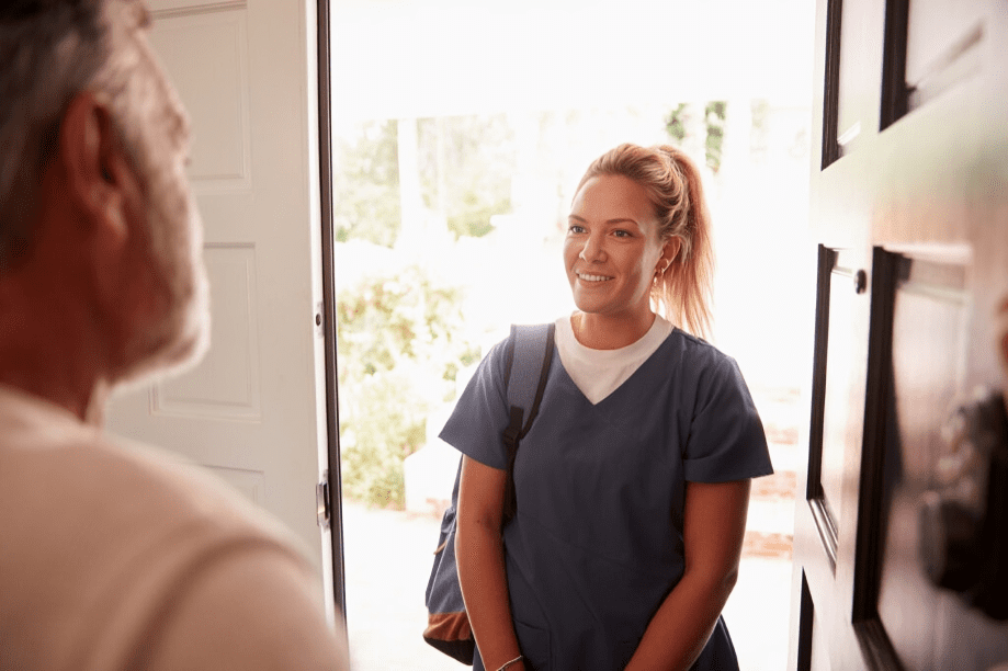 Woman in scrubs standing at doorway.