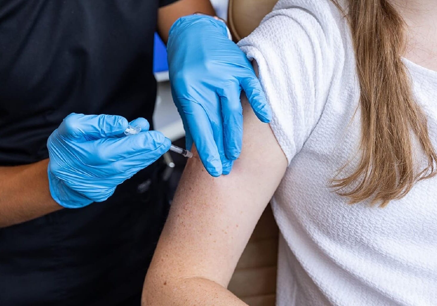 Person receiving vaccination in upper arm.